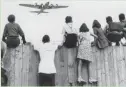  ?? AP ?? West Berlin children watch fleets of U.S. airplanes bringing in supplies to circumvent the Berlin Blockade in this undated file photo.