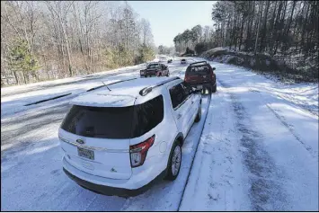  ??  ?? Two vehicles are left abandoned on the side of an ice-covered section of Sixes Road on Sunday in Canton. The Georgia Department of Transporta­tion is urging anyone who spots black ice to call 511.