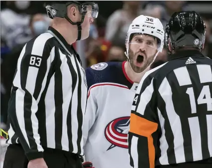  ?? DARRYL DYCK — THE CANADIAN PRESS VIA AP ?? Columbus Blue Jackets’ Boone Jenner, back, protests to referee Trevor Hanson, right, after a penalty was called against Andrew Peeke during the third period of an NHL hockey game Tuesday in Vancouver, British Columbia.