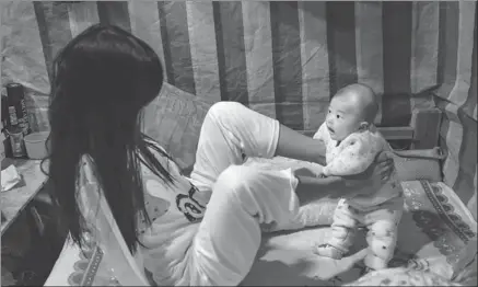  ?? PHOTOS BY CHEN YONGHENG / FOR CHINA DAILY ?? Xiang Liping plays with her child at her home in Shantou, Guangdong province.