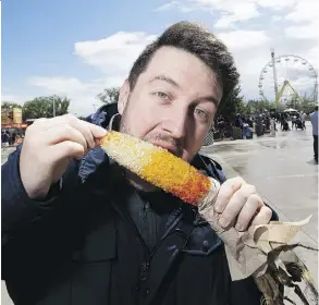  ?? GREG SOUTHAM ?? Reporter Stephen Cook tries Zdebiak Concession­s’ award-winning Mexican Street Style Corn at K-Days on Sunday.