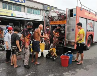 ?? ?? Making every drop count: Hawkers and residents collecting water supplied from a bomba water tanker at Jelutong market.