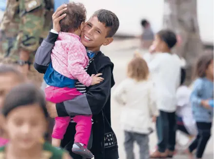  ?? MATTHIAS SCHRADER/AP ?? A recently evacuated Afghan boy carries a child Tuesday at the Ramstein U.S. Air Base in Germany.