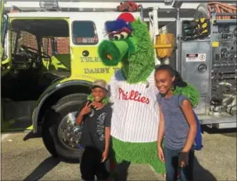  ?? PEG DEGRASSA — DIGITAL FIRST MEDIA ?? Ronda Fields and Darnell Hill, both of Darby Township, posed with the Phillie Phanatic during Tuesday’s National Night Out event in Darby Township. The Phanatic was the promised “surprise celebrity” advertised in pre-event publicity.