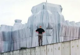  ?? DPA-BILD: KUMM ?? Ein Mann schaut sich im Jahr 1995 auf der Berliner Mauer stehend den verhüllten Reichstag an.