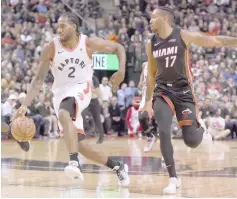 ??  ?? Toronto Raptors forward Kawhi Leonard (left) dribbles the ball past Miami Heat guard Rodney McGruder in the second half at Scotiabank Arena. — USA TODAY Sports photo