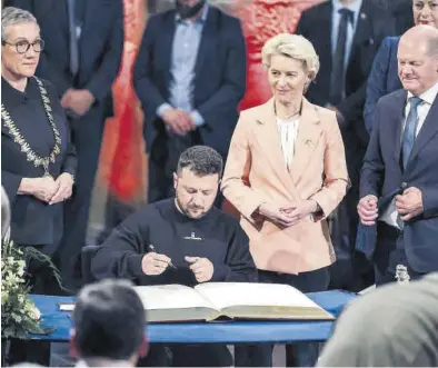  ?? FRIEDEMANN VOGEL / EFE ?? Volodímir Zelenski firma el Libro de Oro de Aquisgrán bajo la mirada de Ursula von der Leyen y Olaf Scholz.