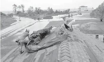  ?? TOM COPELAND/AP ?? Jeff Pyron, left, and Daniel Lilly cover Lilly's roof after Hurricane Florence hit Davis, N.C. on Saturday. Lilly said, “I had my house raised for Irene ’cause I got flooded from the bottom, now i'm getting flooded from the top.”