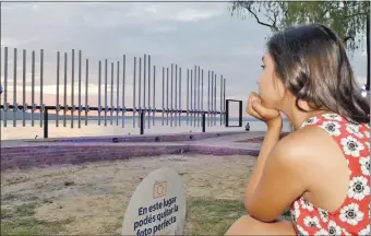  ??  ?? Una joven contempla el sistema acústico que reproduce la conocida guarania “Recuerdo de Ypacaraí”, a orillas del lago que inspiró la canción.