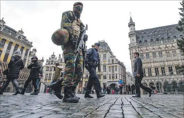  ?? YVES HERMAN / REUTERS ?? Soldados belgas patrullan la céntrica Grand Place de Bruselas tras el refuerzo de la vigilancia