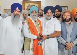  ??  ?? Shiromani Akali Dal president Sukhbir Singh Badal (2R) welcoming former Punjab home minister Brij Bhupinder Singh Lalli into the party with a siropa (robe of honour) and ceremonial sword near Lohian in Shahkot segment on Friday. PARDEEP PANDIT/HT