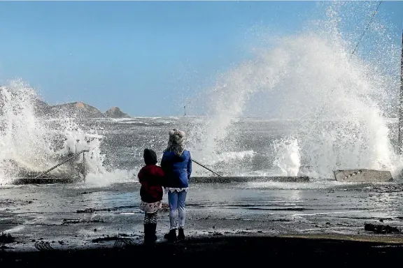  ?? PHOTO: KEVIN STENT ?? Two children watch as the Plimmerton coastline takes a battering from stormy seas at high tide at midday on Sunday. Roads around Porirua were closed on Saturday night and Sunday afternoon because of the rising sea levels and big waves. Read more on P46.