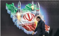  ?? Photo: AFP ?? A man in Tehran yesterday walks past an image depicting missiles being launched from a map of Iran.
