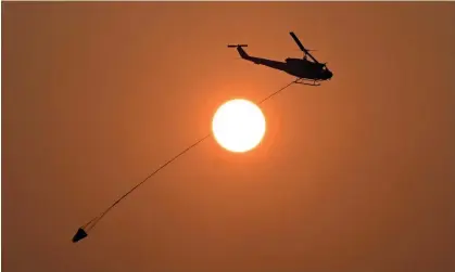  ?? Photograph: Darren England/AAP ?? A water-bombing helicopter fights a bushfire in Queensland in November. The Bureau of Meteorolog­y says the 2023-24 El Niño weather event is over.