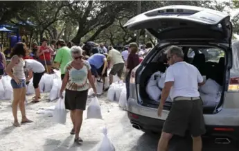  ?? LARA CERRI/THE ASSOCIATED PRESS ?? Helen Conklin carries sandbags as her husband, John Conklin, loads the car in St. Petersburg, Fla.