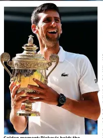  ??  ?? Golden moment: Djokovic holds the trophy after a tumultuous two years