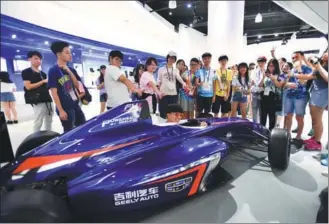  ?? PHILIP CHAU / FOR CHINA DAILY ?? Young people from Hong Kong get a charge from a high-tech race car at Geely Automobile in Hangzhou on Wednesday. They were among 2,000 from the special administra­tive region making a six-day visit to Zhejiang province.