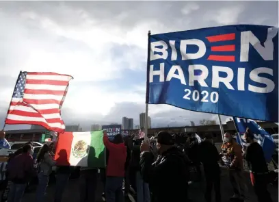  ?? GETTY IMAGES ?? Supporters hold a Biden-Harris flag, an American flag and a Mexican flag while preparing to hold a car parade in Las Vegas on Nov. 7, 2020, to celebrate the outcome of the Nov. 3 election of Joe Biden as president.