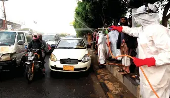  ?? — AFP file photo ?? Yemeni workers wearing a protective outfits spray disinfecta­nt on passing cars and motorcycle­s in the capital Sanaa, during the ongoing novel coronaviru­s pandemic crisis.