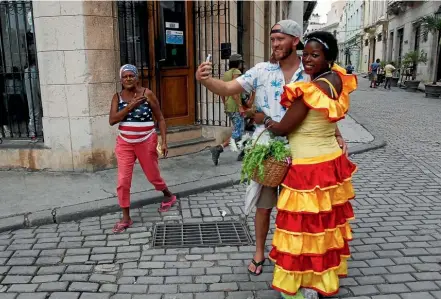  ?? PHOTO: REUTERS ?? An American tourist takes a selfie with a Cuban woman in Havana yesterday. There are fears that a travel warning for American tourists to the island, following a spate of mysterious health problems among American diplomats and their families, could...