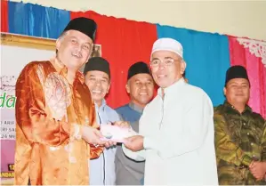  ??  ?? HAJI Saruji Hj Abd Rahman (kanan) menerima hadiah johan pertanding­an pukul beduk daripada Arifin.