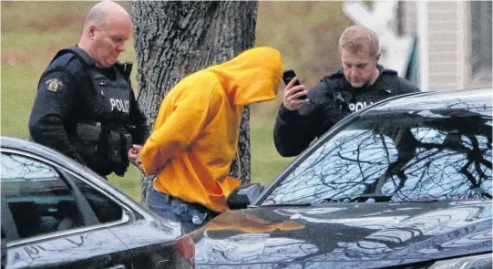  ?? TIM KROCHAK • THE CHRONICLE HERALD ?? A man is led away in handcuffs by RCMP following a high-speed police chase through west-end Halifax on Wednesday that ended on Elliott Street. The two occupants of a vehicle that fled from police face a number of firearm-related charges, RCMP announced Saturday.