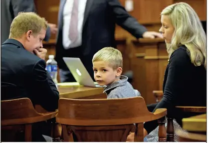  ?? MIKE DE SISTI / MILWAUKEE JOURNAL SENTINEL ?? Mel Russell, 6, sits between his parents, Melbourne III and Nicole, at the Milwaukee County Courthouse in September. As a newborn, Mel was not diagnosed with the metabolic condition that later caused him to have a stroke and suffer brain damage.