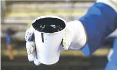  ??  ?? A worker holds a cup of heavy oil. Asia’s petroleum refiners are seeking alternativ­e supplies as they prepare for renewed US sanctions against major oil exporters amid a tight market. — Reuters photo