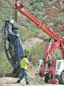  ?? Signal file photo ?? A tow truck operator watches as a Toyota Corolla reaches the surface after being lifted about 200 feet by a crane on to Lake Hughes Road north of Castaic on Sept. 30, 2011. David La Vau survived the crash.