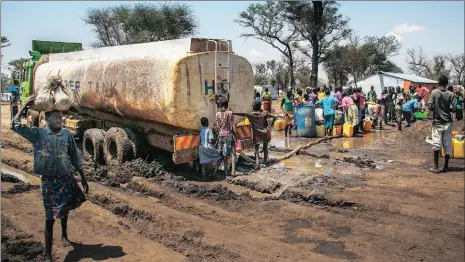  ??  ?? DESPERATE: A water truck is stuck in the mud in Palorinya refugee camp, Uganda. People take the opportunit­y to get much needed water when a water truck gets stuck in the mud after heavy rains. The impending rainy season will only make the situation...