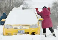  ??  ?? Brenda Gifford clears snow off the top of a car on Brucedale Avenue. More cold weather is expected this week.