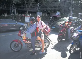  ??  ?? A female motorcycle-taxi driver riding with a passenger in Bangkok.