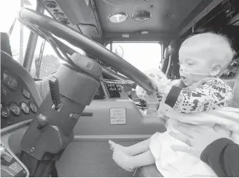  ??  ?? Left: Ten-month-old pediatric patient Justin Roberts is clearly impressed by his first time behind the wheel of a fire truck.