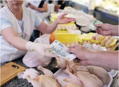  ?? ANDREY RUDAKOV / BLOOMBERG ?? A customer hands over a 1,000-ruble banknote while purchasing farm-produced meat products from a trader at the Dorogomilo­vsky food market in Moscow on Friday.