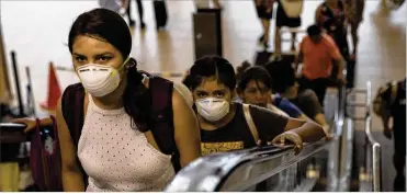  ?? RODRIGO ABD / AP ?? Travelers wearing masks ride an escalator in the internatio­nal airport in Lima, Peru, on Friday, the same day Peruvian President Martin Vizcarra announced the first case of the new coronaviru­s in the country.