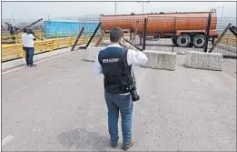  ?? FERNANDO VERGARA/AP ?? An immigratio­n official checks a fuel tanker, cargo trailers and makeshift fencing, used as barricades by Venezuelan authoritie­s to block humanitari­an aid from entering.