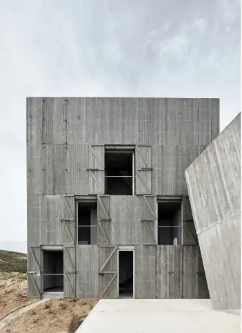  ??  ?? LE VOLUME DE BÉTON qui accueille les chambres et les salles de bains s’ouvre sur un côté par des fenêtres protégées par de grands volets en bois.