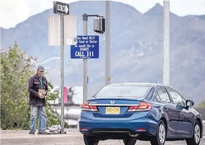  ?? ROBERTO E. ROSALES ?? A panhandler stands near a city sign intended to help those in need.