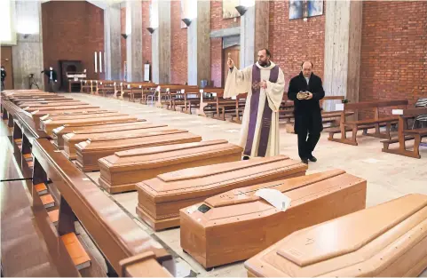  ?? AFP ?? Priest Don Marcello gives a blessing to the coffins of deceased people inside the church of San Giuseppe in Seriate, Italy on Saturday.