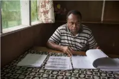  ??  ?? William Koiatuna, a community leader in the Pomio area, looks at petitions signed by local communitie­s against proposed logging and oil palm plantation operations (Fabio Erdos/Panos)