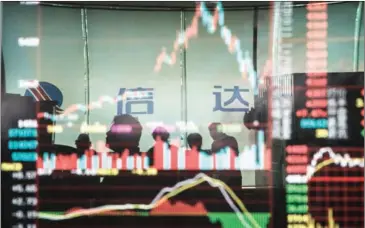  ?? GILLES SABRIE/THE NEW YORK TIMES ?? Stock investors are reflected on a computer screen showing stock prices at a brokerage house in Beijing on July 20, 2015. The world’s third-largest market has widened access to its bond market, a move which will integrate the economic giant more deeply...