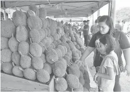  ?? — Gambar Bernama ?? PILIH: Seorang pengunjung tertarik dengan buah durian yang dijual pada Program Jualan Jimat Belanja Pasca Aidilfitri @ MyFarm Outlet, Putrajaya anjuran Lembaga Pemasaran Pertanian Persekutua­n (FAMA) semalam.