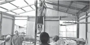  ??  ?? PENDUDUK kampung membantu membaiki bumbung rumah pengadu yang telah rosak dibadai ribut pada Khamis.