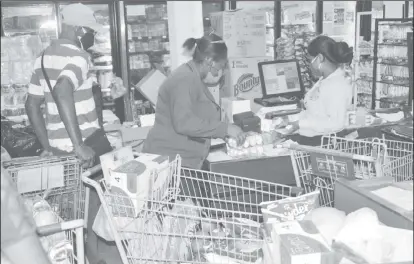  ??  ?? Staff at the Survival Supermarke­t assisting with checking and packing the trolleys for the beneficiar­ies. (DPI Photo)