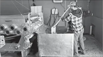  ?? HENDERSON COUNTY TOURISM ?? A worker presses apples to make hard cider at Bold Rock, a leading craft cider producer.