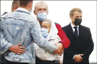  ?? ASSOCIATED PRESS ?? France President Emmanuel Macron (right) stands as Sophie Petronin (center) a French aid worker held hostages for four years by Islamic extremists in Mali, is greeted by relatives upon her arrival Friday at the Villacoubl­ay military airport near Paris.