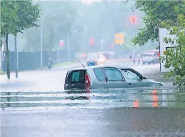  ?? FOTOS: DPA ?? In Oranienbur­g in Brandenbur­g wurden Autofahrer vom starken Regenfall überrascht. Innerhalb weniger Minuten standen ganze Straßenzüg­e unter Wasser.