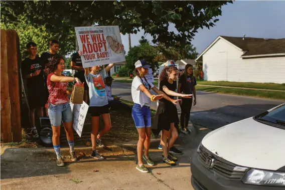  ?? ?? Teenagers from a church group try to stop a car as it enters the Trust Women clinic, which draws protesters trying to prevent women from having abortions.