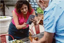  ?? ?? Susie Lafredo takes a video of a cheesy sandwich at Elsewhere Garden Bar & Kitchen to showcase on Facebook.