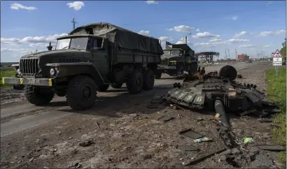  ?? AP ?? GROUND GRIND: Ukrainian army trucks pass the remains of a tank Friday in the northern reaches of Kharkhiv, Ukraine, which has seen intense combat in recent days.